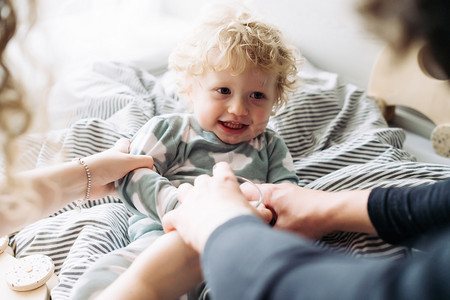 父母和他们的小卷发的儿子在睡衣玩耍, 笑和有乐趣