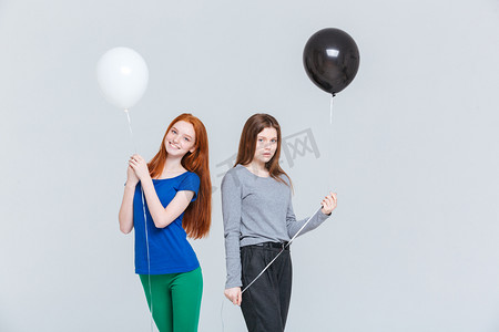 两个年轻妇女抱着黑色和白色的气球