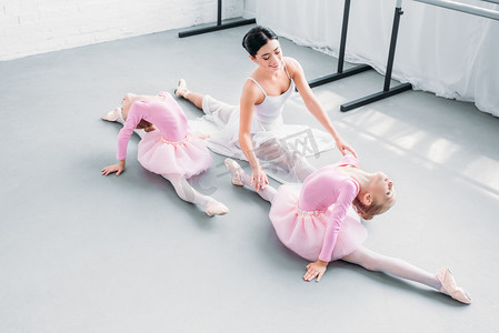 粉红小摄影照片_高视角的微笑年轻教师与可爱的小芭蕾舞运动在芭蕾学校