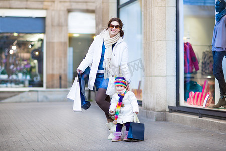 母亲和她蹒跚学步的女儿享受购物