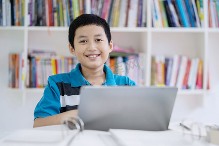 在图书馆使用笔记本电脑时, 亚洲青春期学生的照片看起来很开心