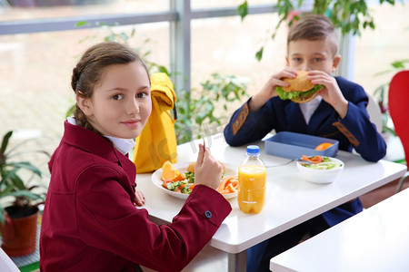 孩子们吃午饭时坐在自助餐桌旁