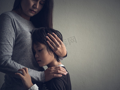 伤心的小男孩被抱着由他的母亲在家里. 
