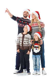 圣诞毛衣摄影照片_快乐的家庭与孩子在圣诞毛衣和圣诞老人的帽子, 父亲显示一些孤立的白色