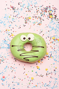 绿色搞笑惊讶在粉红色的背景上的甜甜圈