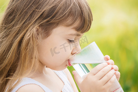 嘴唇标签摄影照片_孩子他手里拿着一杯水。选择性的焦点. 