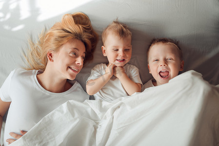 幸福的家庭，在早晨躺在白色的毯子下.