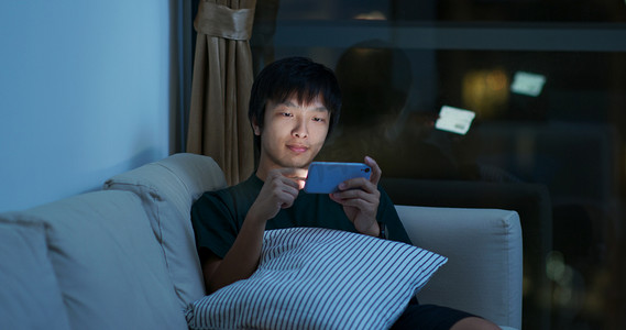 男人晚上在手机上玩网络游戏