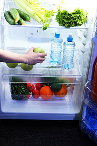 女人的手伸向食物从冰箱里，关闭