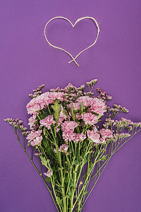 紫罗兰色的美丽的粉红色的花朵和心形的绳子花束
