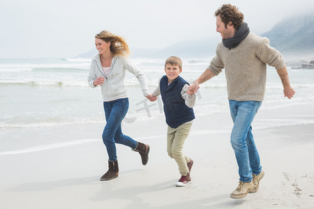 šťastná rodina tří běží na pláži幸福的家庭，三个在海滩上运行