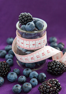 饮食餐。黑莓和蓝莓在玻璃罐子里与措施