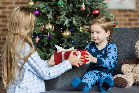 可爱的孩子穿着睡衣在家里拿圣诞礼物 