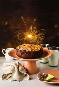 桌子上的无麸质和纯素巧克力杏仁古蛋糕, 上面有燃烧的节日火花