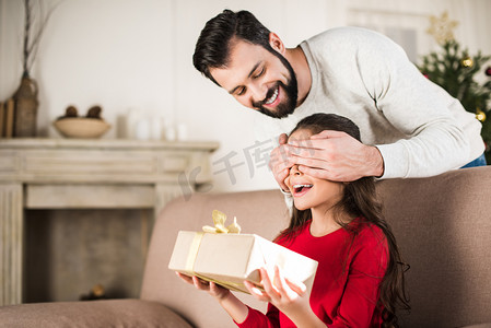 父亲掩护女儿的眼睛从后面和赠送礼物
