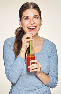 长头发的微笑的妇女喝红色果汁反对白色背景 