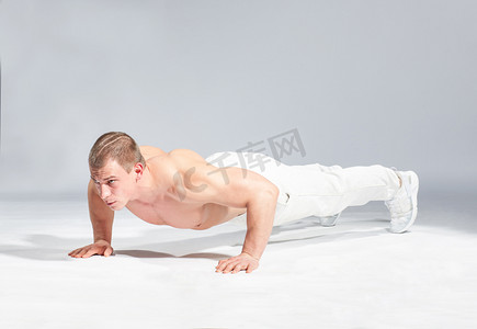 年轻肌肉型男做俯卧撑灰色背景