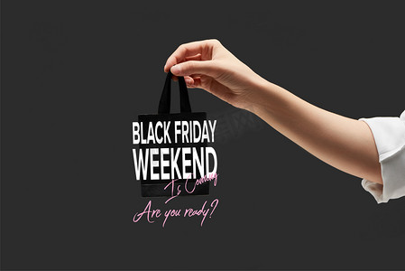 小促销标志摄影照片_女性手持黑色小购物袋与黑色黑色星期五周末插图的剪影