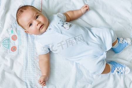 Portrait of a pretty little baby , lying on a light blanke