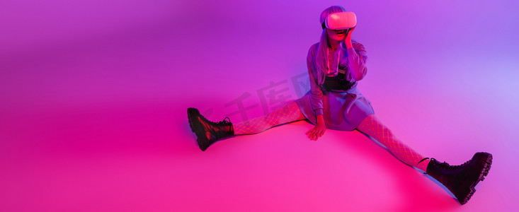 全长女性在虚拟现实耳机坐在紫色与粉色照明，横幅