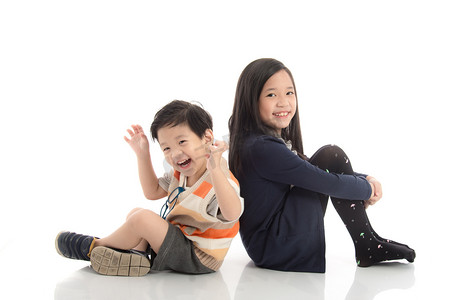 抱抱摄影照片_两个快乐的亚洲孩子坐，斜倚在对方的存在