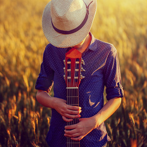 十几岁的男孩在与声学吉他，在户外的帽子