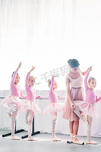 年轻老师摄影照片_教可爱的孩子在芭蕾学校跳舞的年轻妇女 