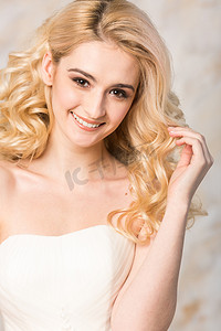 在明亮的背景上的白色的婚纱礼服特写美丽卷发华丽微笑的金发新娘的肖像.