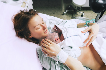 医疗生活摄影照片_妈妈抱着她刚出生的婴儿在医院分娩后. 