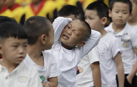 学期摄影照片_2 0 1 8年 8月 2 7日, 在中国西南贵州省贵阳市一所小学, 一名年轻学生和其他学生在参加新学期的升旗仪式时做鬼脸. 