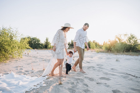 帅气的爸爸摄影照片_快乐的家庭与儿子牵手在海滩上