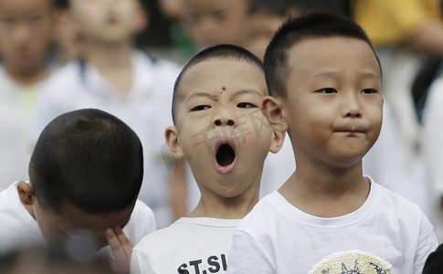 学校升旗仪式摄影照片_2 0 1 8年 8月 2 7日, 在中国西南贵州省贵阳市一所小学, 一名年轻学生在参加新学期升旗仪式时打哈欠. 
