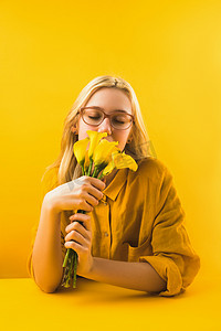 庆祝拉花摄影照片_女孩在黄色拿着美丽的黄色马蹄莲百合花
