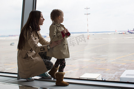 航空母摄影照片_母亲和小女儿在机场航站楼窗外望去