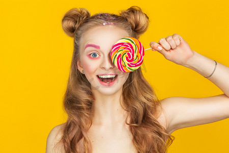 红色大嘴唇摄影照片_幸福的年轻女人，与大七彩的棒棒糖在黄色背景