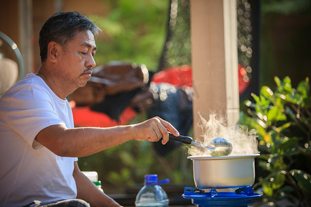 火锅摄影照片_老人对液化石油气燃气灶火锅烹饪早餐食品