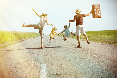 幸福的家庭彼此牵手阳光灿烂的乡村道路上