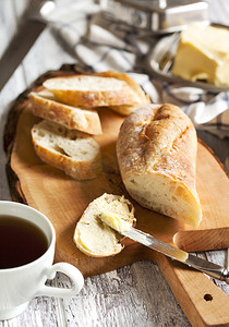 棕色的桌子摄影照片_面包与黄油和杯茶木制的桌子上.