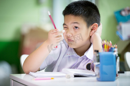 学生写做作业摄影照片_年轻的亚洲男孩做作业