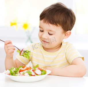 可爱的小男孩吃蔬菜沙拉
