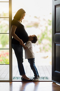 散文诗二首摄影照片_年幼的儿子在门口中拥抱怀孕的妈妈