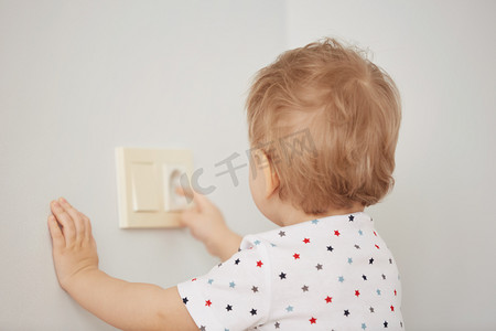 好奇的小男孩玩电插头。试图将它插入到电源插座。在家里的危险