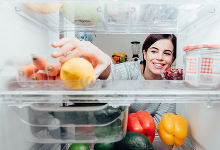 制冷器摄影照片_女人采取从冰箱的柠檬
