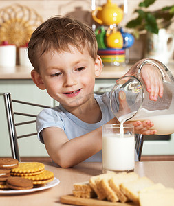 牛奶翻倒摄影照片_快乐的孩子倒牛奶从水罐
