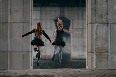摇滚少年摄影照片_他们手牵手一起在城市桥梁下的两个女孩.