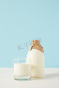 牛奶玻璃和牛奶在蓝色背景纸包装的瓶子特写镜头 