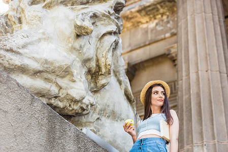 水果摄影照片_年轻时髦的女人在帽子与新鲜的苹果在街上的肖像