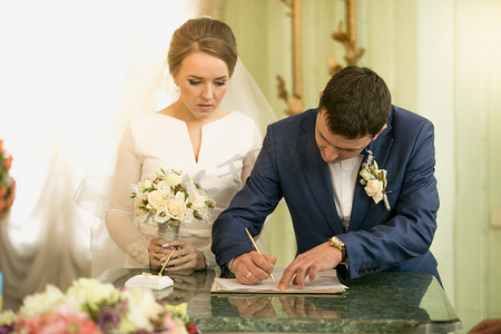 年轻新郎在登记处签署结婚合同的特写