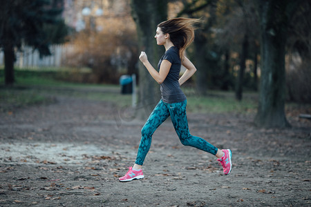 年轻运动的女孩在公园跑步