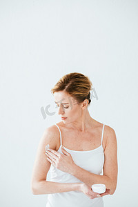 商务医疗保险摄影照片_有吸引力的妇女与皮肤疾病持有容器，并应用化妆品霜在白色 